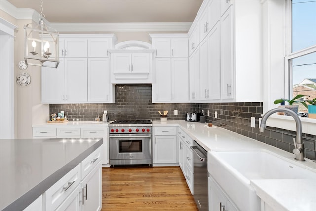 kitchen with sink, white cabinetry, light hardwood / wood-style flooring, pendant lighting, and stainless steel appliances