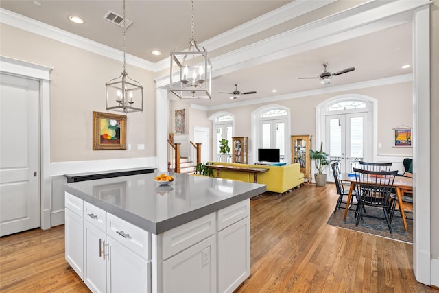 kitchen with french doors, light hardwood / wood-style flooring, hanging light fixtures, ornamental molding, and white cabinets