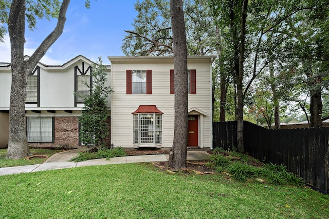 view of front of house with a front lawn, fence, and brick siding