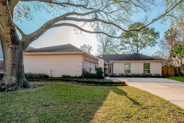 view of front of house featuring a front yard, brick siding, and fence