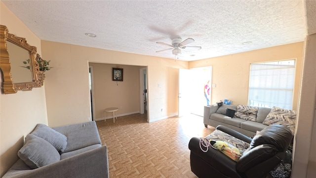 living room with ceiling fan, light parquet flooring, and a textured ceiling