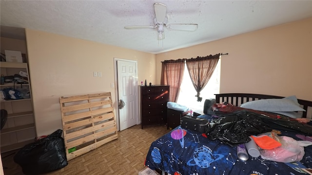 bedroom with ceiling fan, parquet flooring, and a textured ceiling