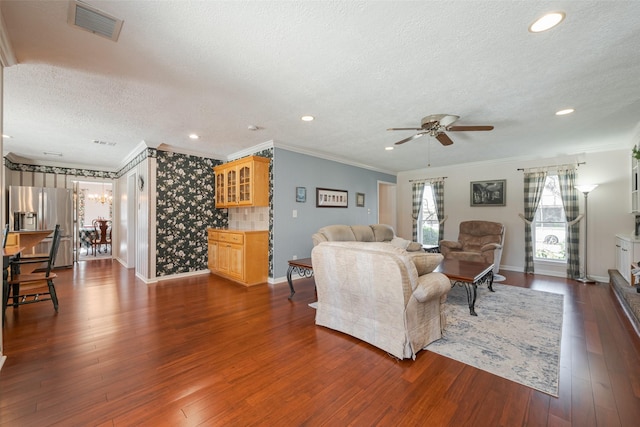 living room with a textured ceiling, dark wood-style flooring, plenty of natural light, and visible vents