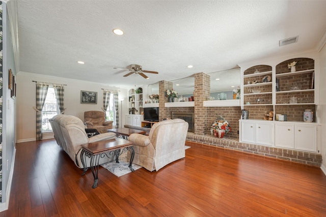 living room with a brick fireplace, visible vents, a textured ceiling, and hardwood / wood-style floors