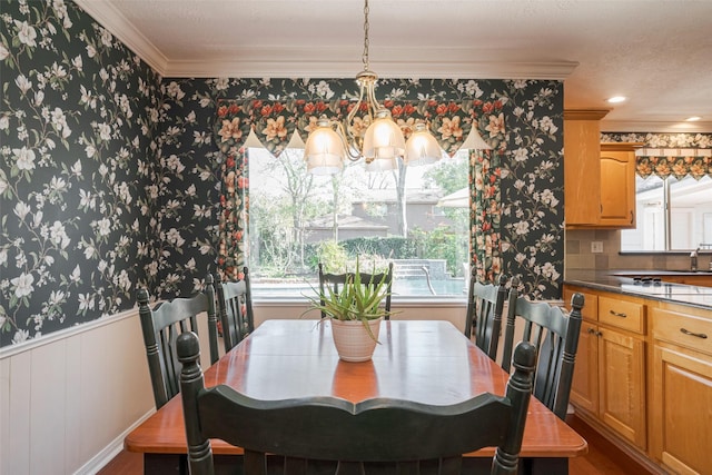 dining room with crown molding, wainscoting, a textured ceiling, wood finished floors, and wallpapered walls