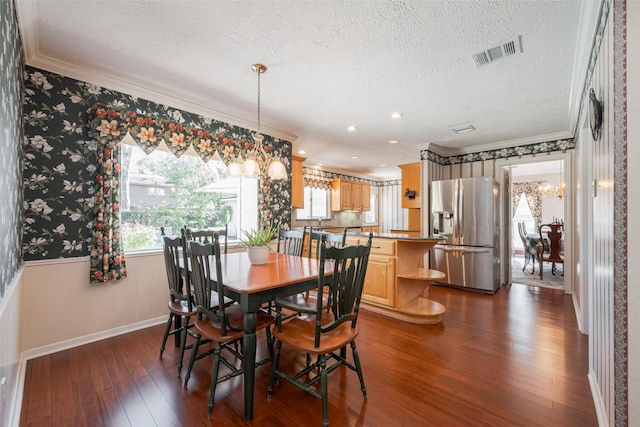 dining space with wallpapered walls, crown molding, visible vents, and a wainscoted wall