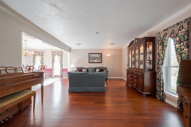 living room with a textured ceiling, ornamental molding, wood finished floors, and an inviting chandelier