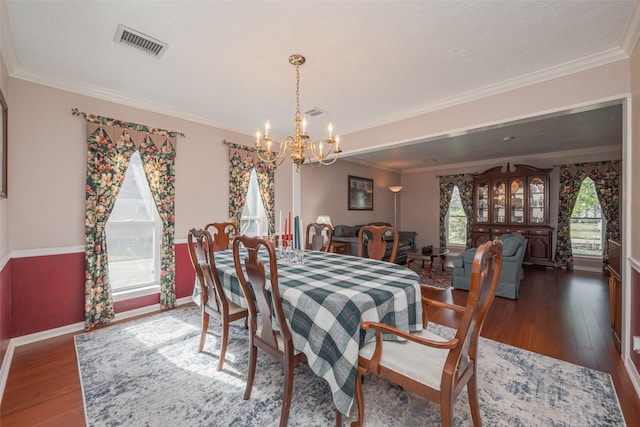 dining space featuring an inviting chandelier, crown molding, visible vents, and wood finished floors