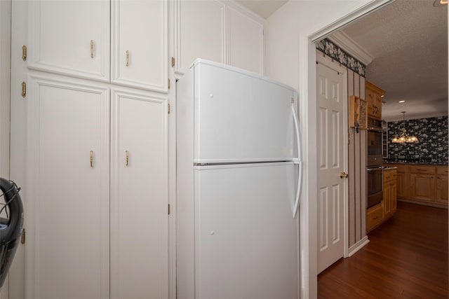 kitchen with double oven, freestanding refrigerator, white cabinets, and dark wood finished floors