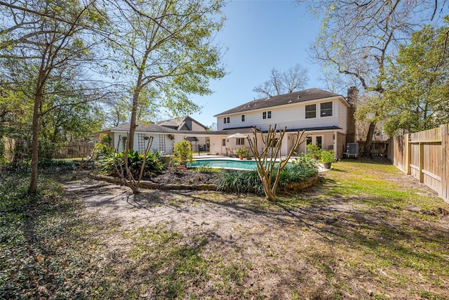 back of house featuring a fenced backyard, a chimney, and a fenced in pool