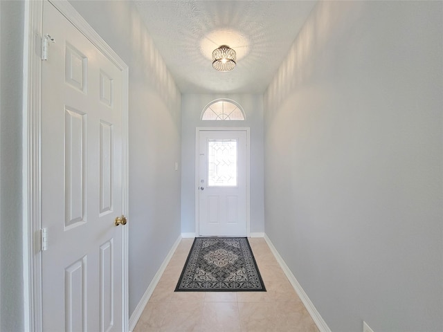 doorway to outside with light tile patterned flooring and a textured ceiling