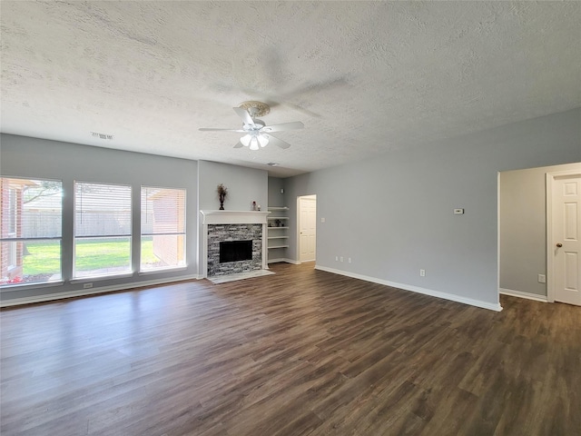 unfurnished living room featuring dark wood-type flooring, ceiling fan, a fireplace, and a textured ceiling