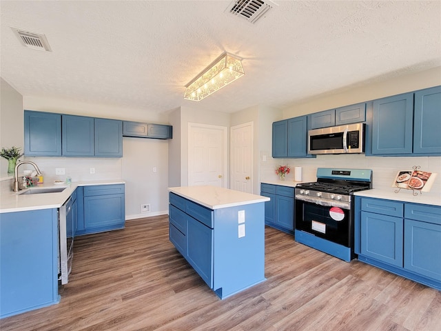 kitchen featuring blue cabinets, sink, a kitchen island, stainless steel appliances, and light hardwood / wood-style floors