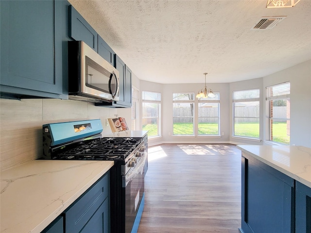 kitchen with blue cabinets, appliances with stainless steel finishes, light stone counters, and light wood-type flooring