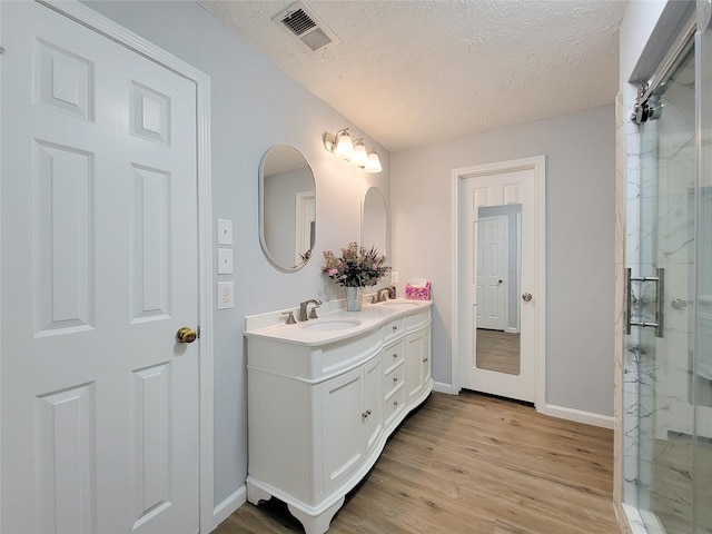 bathroom with vanity, an enclosed shower, hardwood / wood-style floors, and a textured ceiling