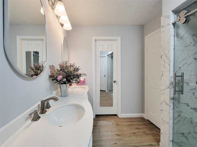 bathroom featuring hardwood / wood-style flooring, vanity, a shower with door, and a textured ceiling