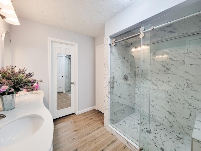 bathroom with wood-type flooring, sink, a textured ceiling, and a shower with shower door