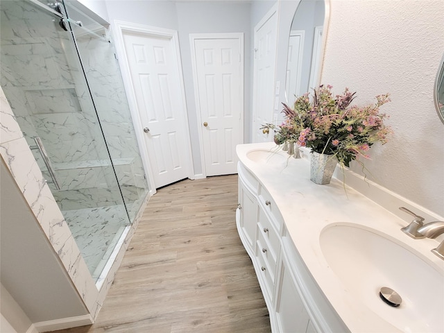 bathroom with hardwood / wood-style floors, vanity, and a tile shower