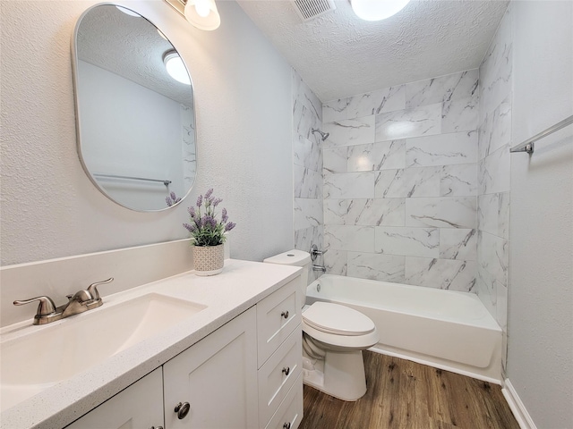 full bathroom with tiled shower / bath, wood-type flooring, vanity, toilet, and a textured ceiling