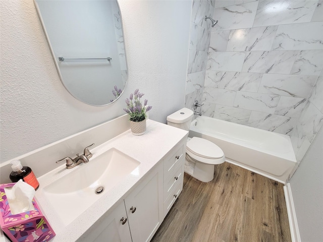 full bathroom with hardwood / wood-style flooring, vanity, tiled shower / bath, and toilet