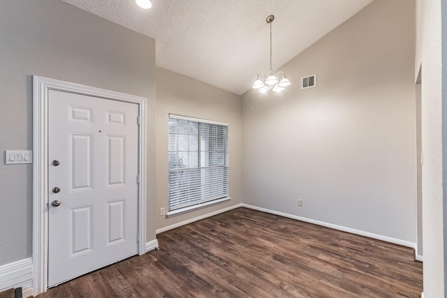 entrance foyer with a notable chandelier, dark wood-type flooring, vaulted ceiling, and a textured ceiling