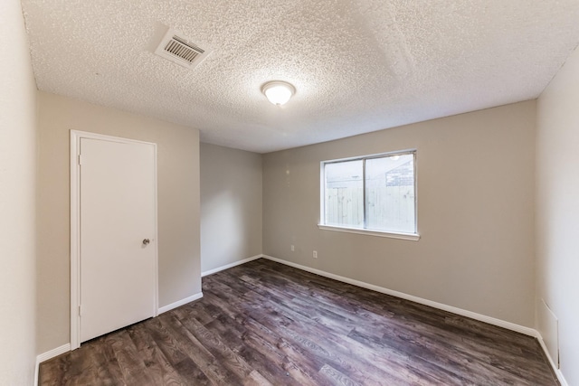 empty room featuring dark hardwood / wood-style floors and a textured ceiling