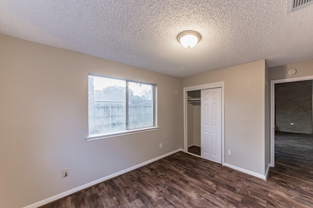 unfurnished bedroom with a textured ceiling, dark hardwood / wood-style flooring, and a closet