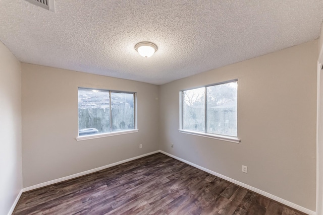 spare room featuring dark hardwood / wood-style flooring and a textured ceiling