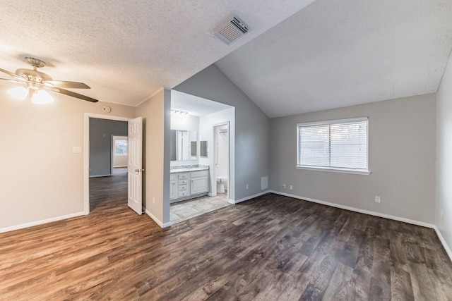 spare room with ceiling fan, dark wood-type flooring, a textured ceiling, and vaulted ceiling