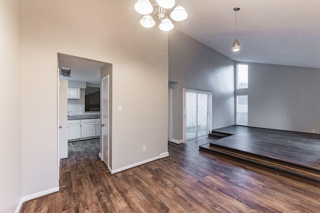 unfurnished living room with dark hardwood / wood-style floors, a notable chandelier, and high vaulted ceiling