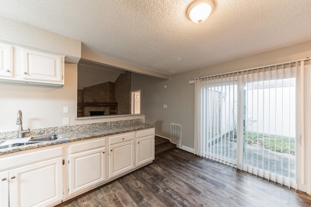 kitchen featuring stone counters, dark hardwood / wood-style floors, sink, and white cabinets