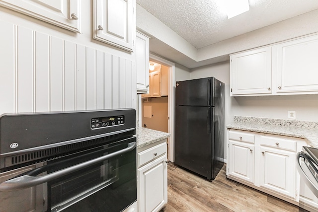 kitchen featuring black appliances, a textured ceiling, light hardwood / wood-style flooring, light stone countertops, and white cabinets