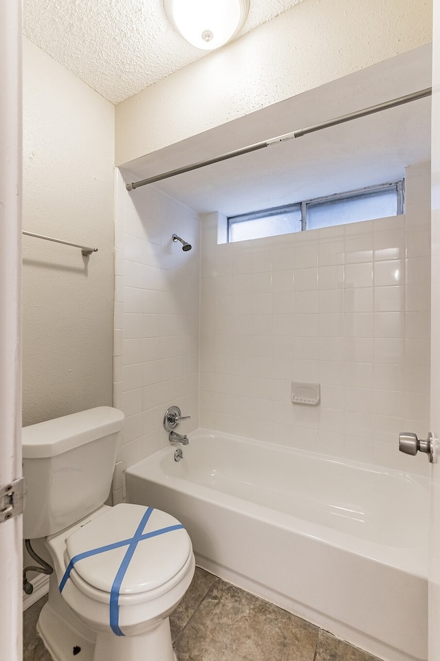 bathroom with tiled shower / bath combo, a textured ceiling, and toilet