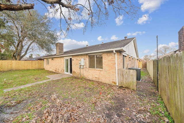 back of property with central AC and a lawn