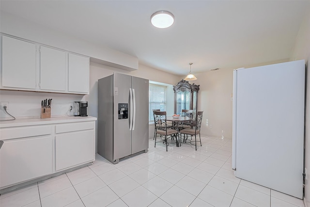 kitchen featuring visible vents, stainless steel refrigerator with ice dispenser, white cabinetry, freestanding refrigerator, and light countertops