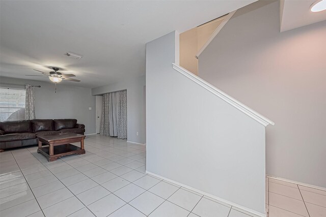 living room with light tile patterned flooring, a ceiling fan, visible vents, and baseboards