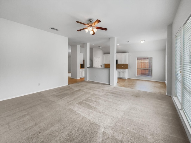 unfurnished living room featuring lofted ceiling, light carpet, visible vents, baseboards, and a ceiling fan