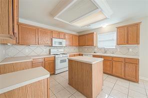 kitchen featuring white appliances, a center island, decorative backsplash, and light tile patterned floors