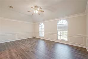 empty room with crown molding, dark wood-type flooring, and vaulted ceiling