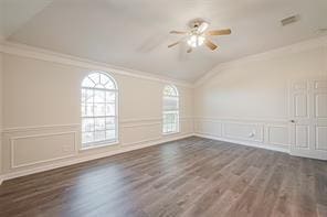 spare room featuring dark wood-type flooring, ceiling fan, crown molding, and vaulted ceiling