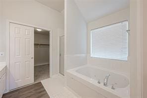 bathroom with tiled tub, vanity, lofted ceiling, and hardwood / wood-style flooring