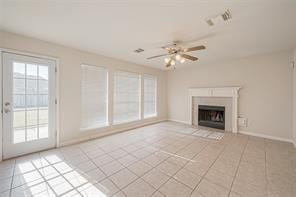 unfurnished living room with ceiling fan, light tile patterned floors, and a wealth of natural light