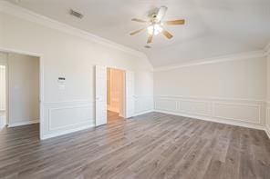 unfurnished room with dark wood-type flooring, vaulted ceiling, ornamental molding, and ceiling fan