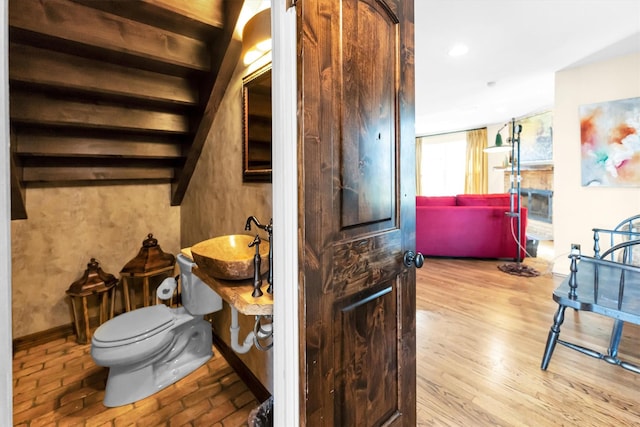 interior space featuring recessed lighting, toilet, a sink, wood finished floors, and baseboards