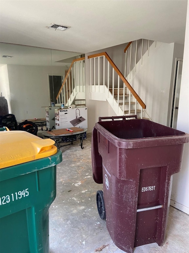 living area featuring stairway, visible vents, and unfinished concrete floors