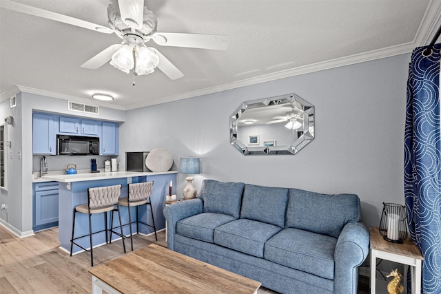 living room featuring ceiling fan, ornamental molding, sink, and light hardwood / wood-style floors