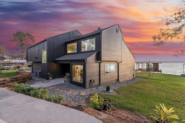 view of front of house featuring a water view, a yard, and central AC unit