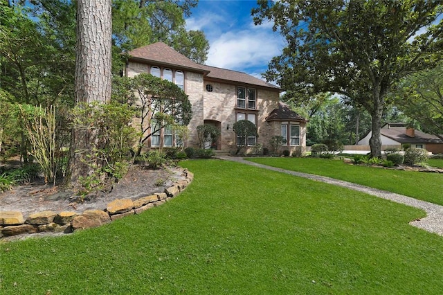 view of front facade with brick siding and a front yard