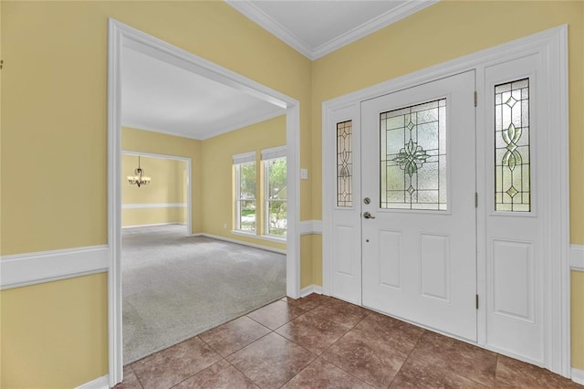 carpeted entrance foyer featuring ornamental molding, a notable chandelier, and baseboards