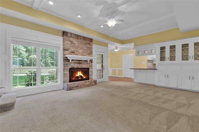 unfurnished living room with beam ceiling, light carpet, ceiling fan, and a fireplace